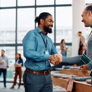 Happy businessmen greeting while attending an education event at conference hall.